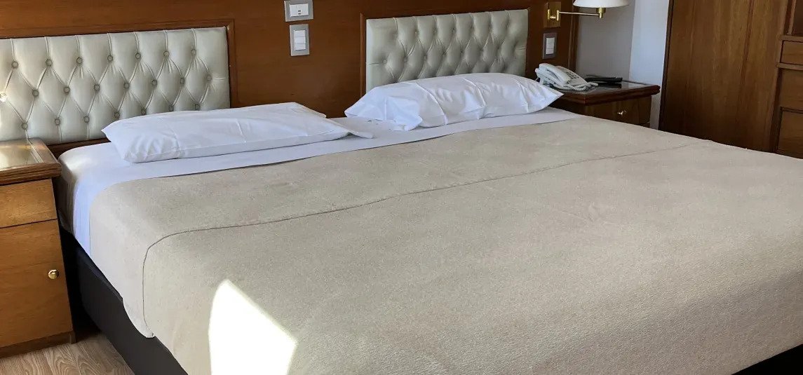 Quarto superior com cama de casal e vista cidade